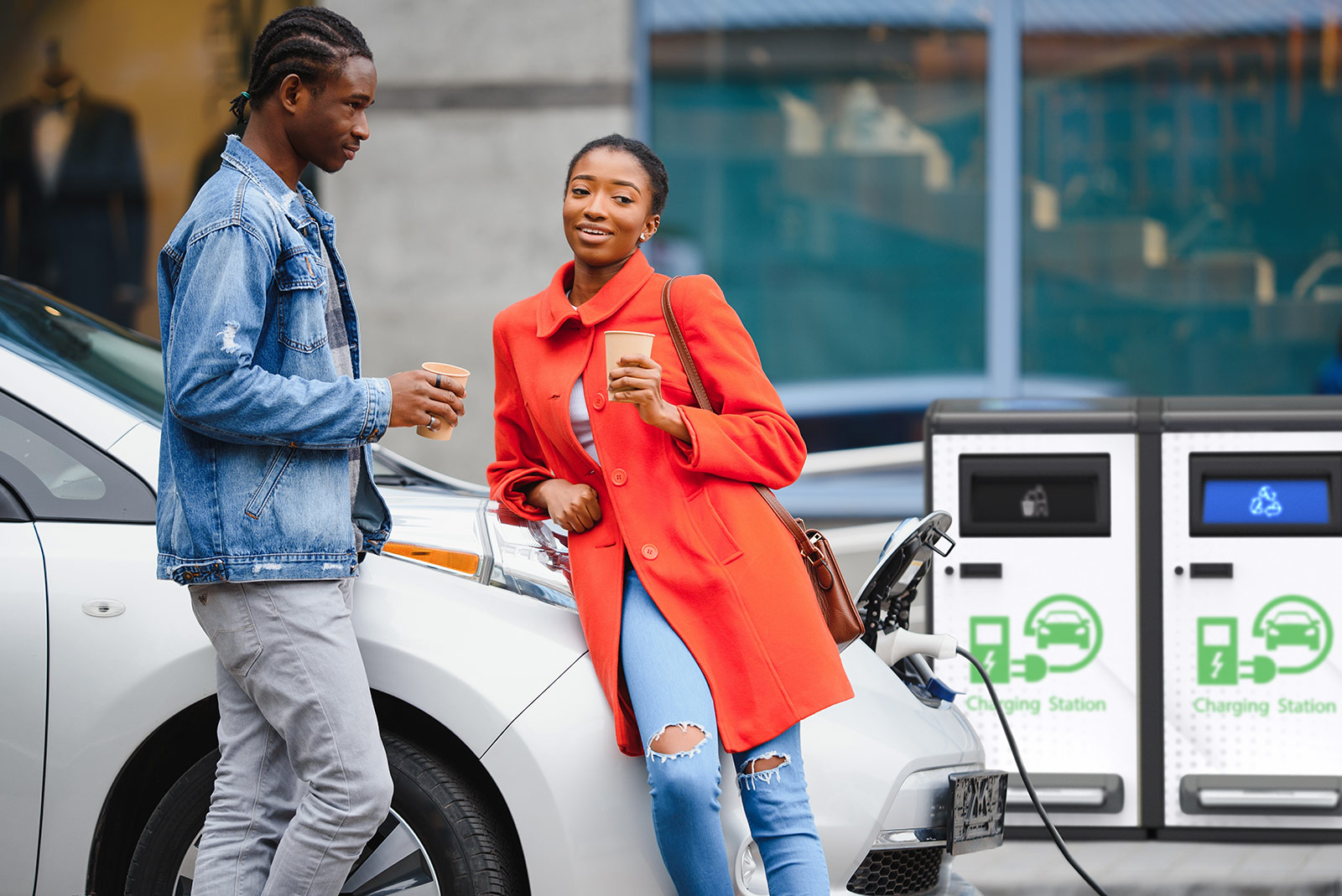 two people with their car in front of a bigbelly solar trash can