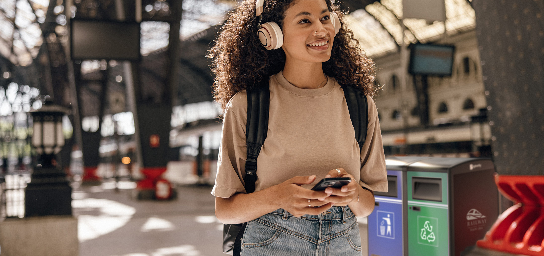 happy woman walking through a clean train station featuring a trash compactor in the background